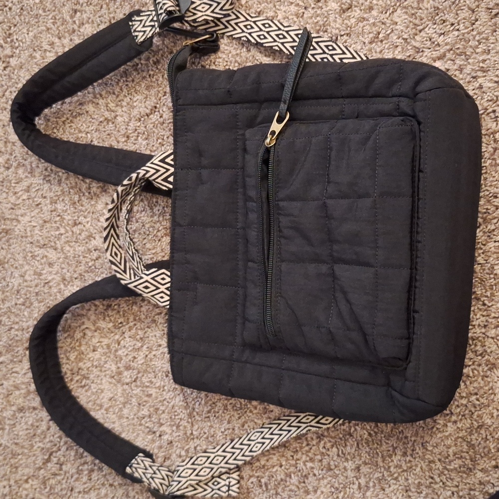 Black quilted nylon backpack with black and white handles and straps